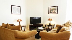 Ein Wohnzimmer mit zwei Sofas, einem Fernseher und zwei Beistelltischen mit Lampen.