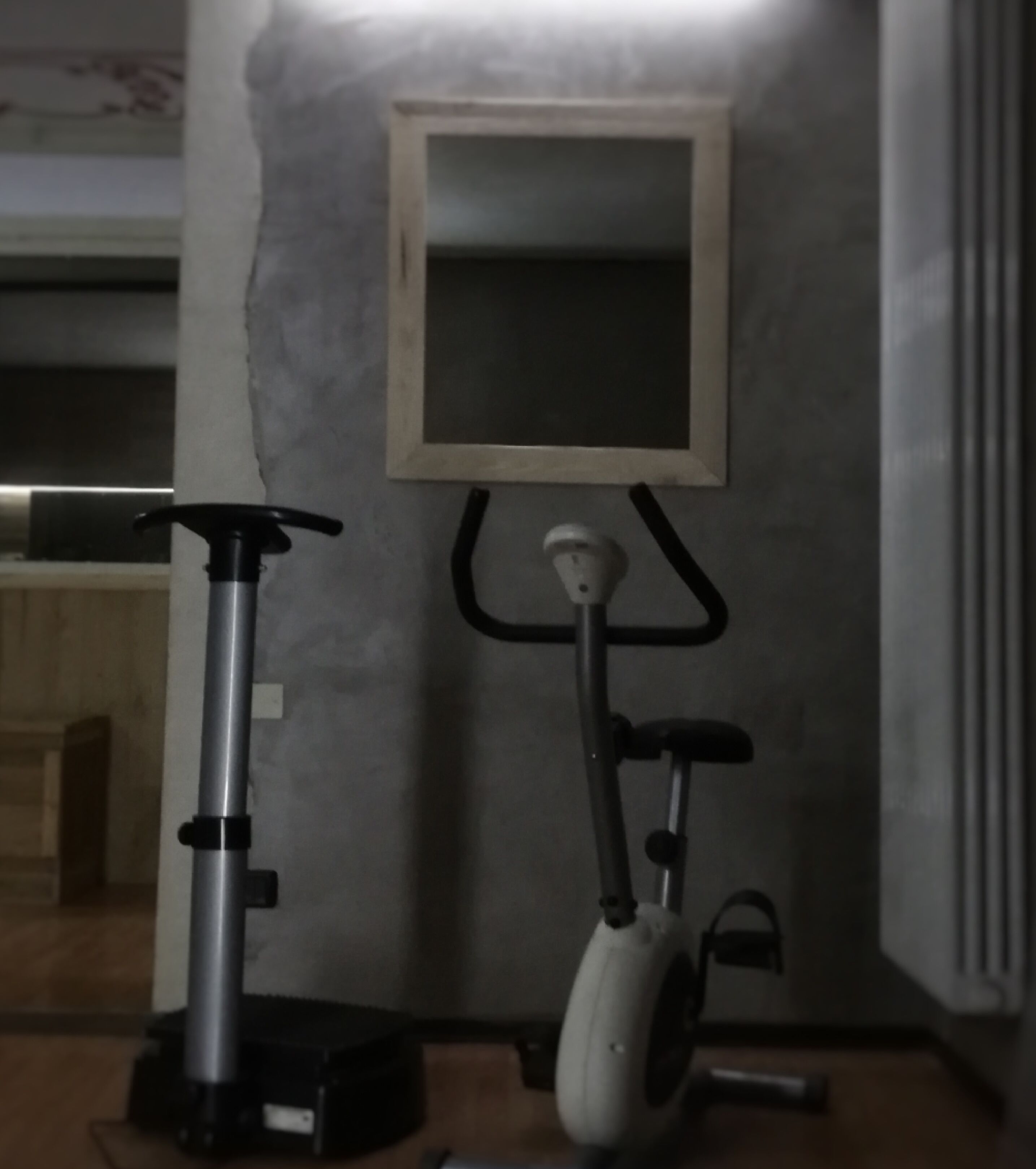 A room with a wall-mounted TV, a standing exercise bike, and a stationary bike.