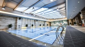 Piscina com piso de azulejos e teto de vidro.