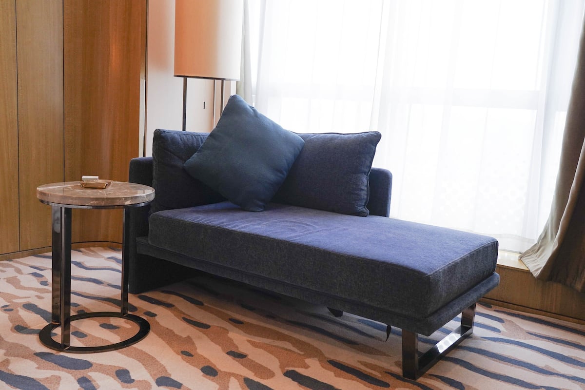 Ein modernes Zimmer mit einer Couch, einem kleinen runden Tisch und einem gemusterten Teppich.