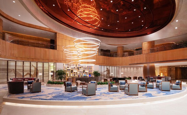 A spacious lobby with a central seating area, multiple levels, and a distinctive ceiling design.