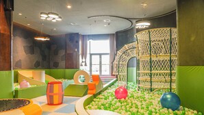 A children's play area with a ball pit, soft play structures, and a netted climbing structure.