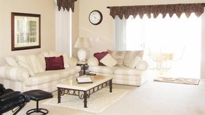 A living room with a ceiling fan, two couches, a coffee table, and a clock on the wall.
