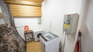 A laundry room with a washing machine, dryer, and a utility meter. - ManMan House (New Taipei City)