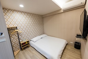 A modern hotel room with a patterned wallpaper, a bed with white linens, a wooden nightstand, and a mounted TV.