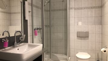 Un bany modern amb dutxa de vidre, un lavabo amb mirall i un vàter.