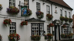 A white building with multiple windows adorned with hanging flower baskets. - The Angel Inn (Worksop)