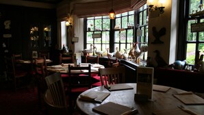 A dimly lit restaurant with wooden furniture and decorative swan figures. - The Angel Inn (Worksop)