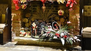 A fireplace with Christmas decorations, including red and gold ornaments, and a mirror above it. - The Angel Inn (Worksop)