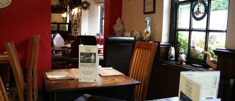 A cozy restaurant interior with wooden furniture, a menu on the table, and a view through the window.