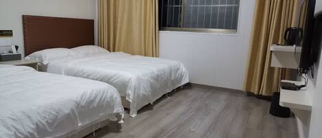 A hotel room with two beds, a nightstand, a TV, and a window with curtains.