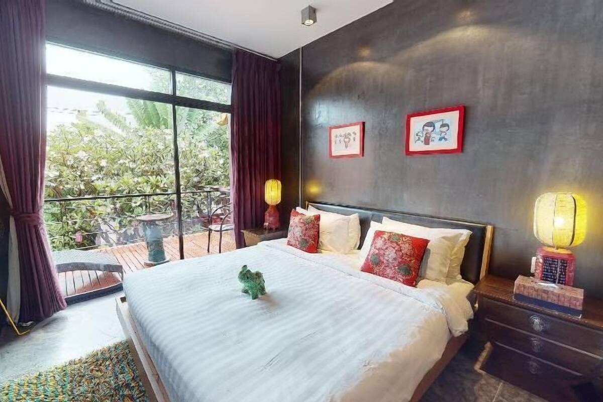 A modern hotel room with a large bed, a balcony, and two wall-mounted lamps.