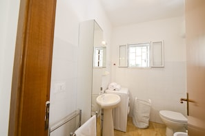A bathroom with a sink, mirror, toilet, and a shower area. - Villa d'Itria with Trullo by Wonderful Italy (Ostuni)