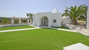 A modern house with a white exterior, a small arched entrance, and a well-maintained lawn. - Villa d'Itria with Trullo by Wonderful Italy (Ostuni)