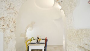 A dining area with a white table set for four, surrounded by stone walls. - Villa d'Itria with Trullo by Wonderful Italy (Ostuni)