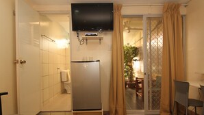 Une petite salle de bain comprenant des toilettes, un lavabo et un téléviseur fixé au-dessus du miroir.