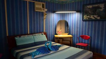 Une chambre d’hôtel avec un papier peint à rayures, un lit recouvert d’une courtepointe à rayures, un bureau avec un miroir, une chaise rouge et un climatiseur fixé au mur.