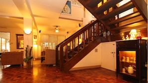 Un escalier en bois avec une rampe, un plancher en bois, une porte blanche et une étagère ornée d’objets décoratifs.
