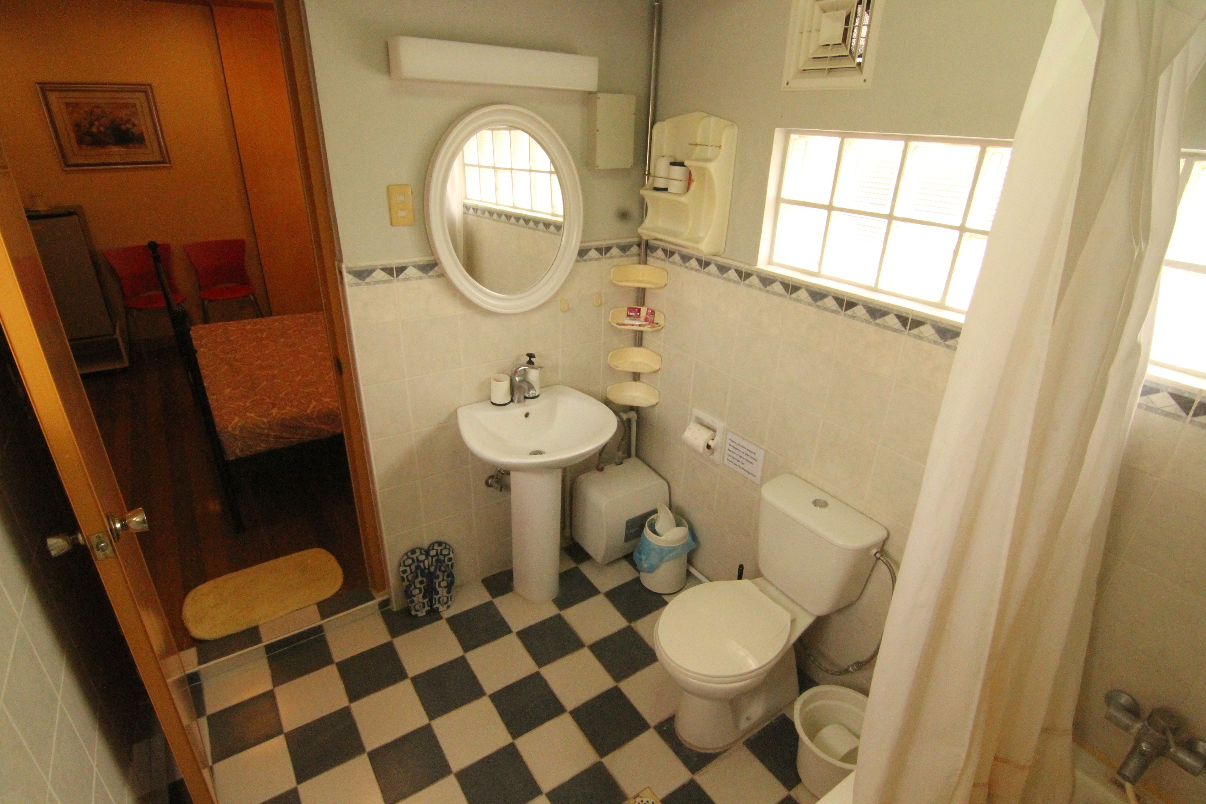 A bathroom with a checkered floor, a sink, a toilet, and a shower curtain.