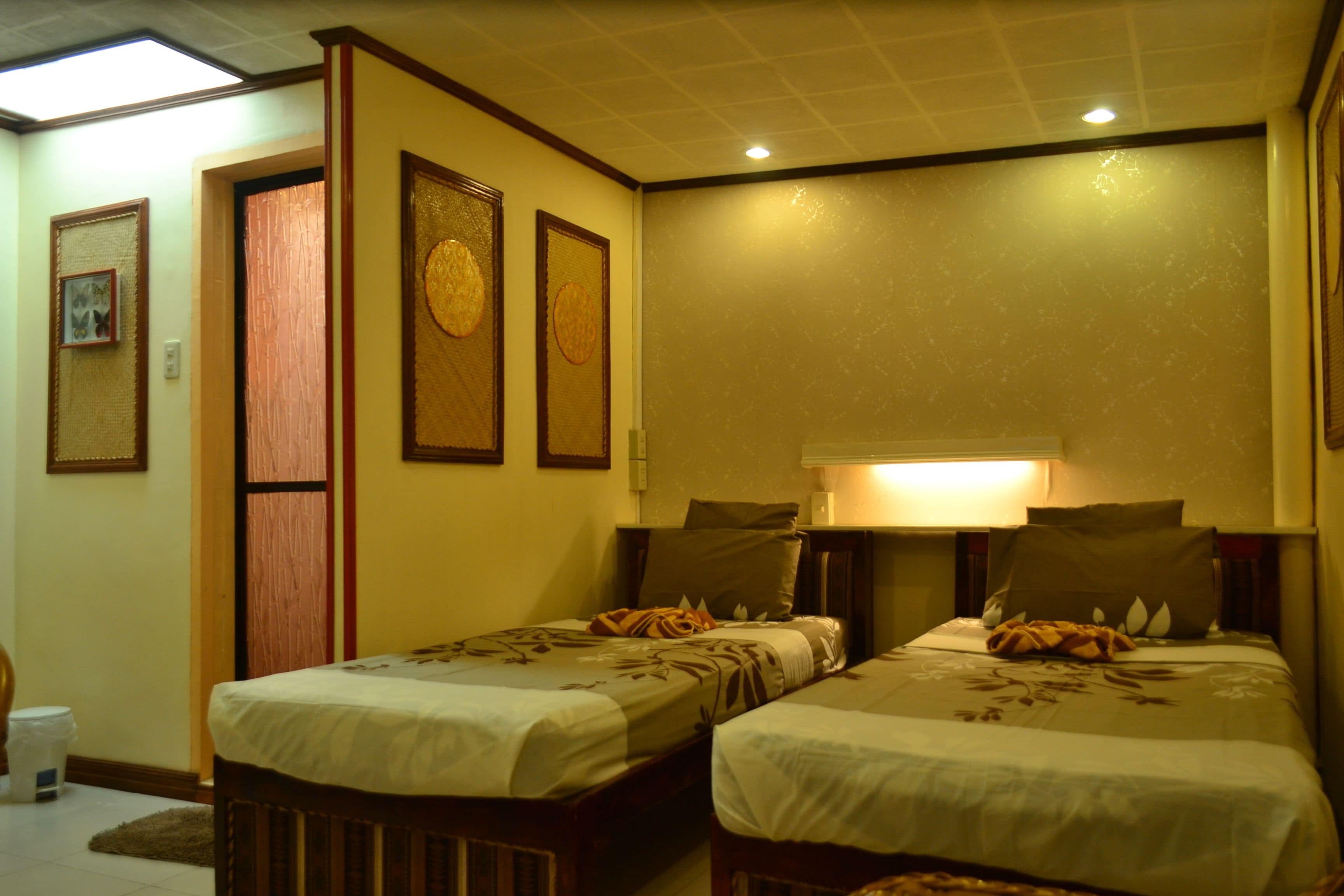A hotel room with two beds, a wooden door, and a wall with three circular decorations.