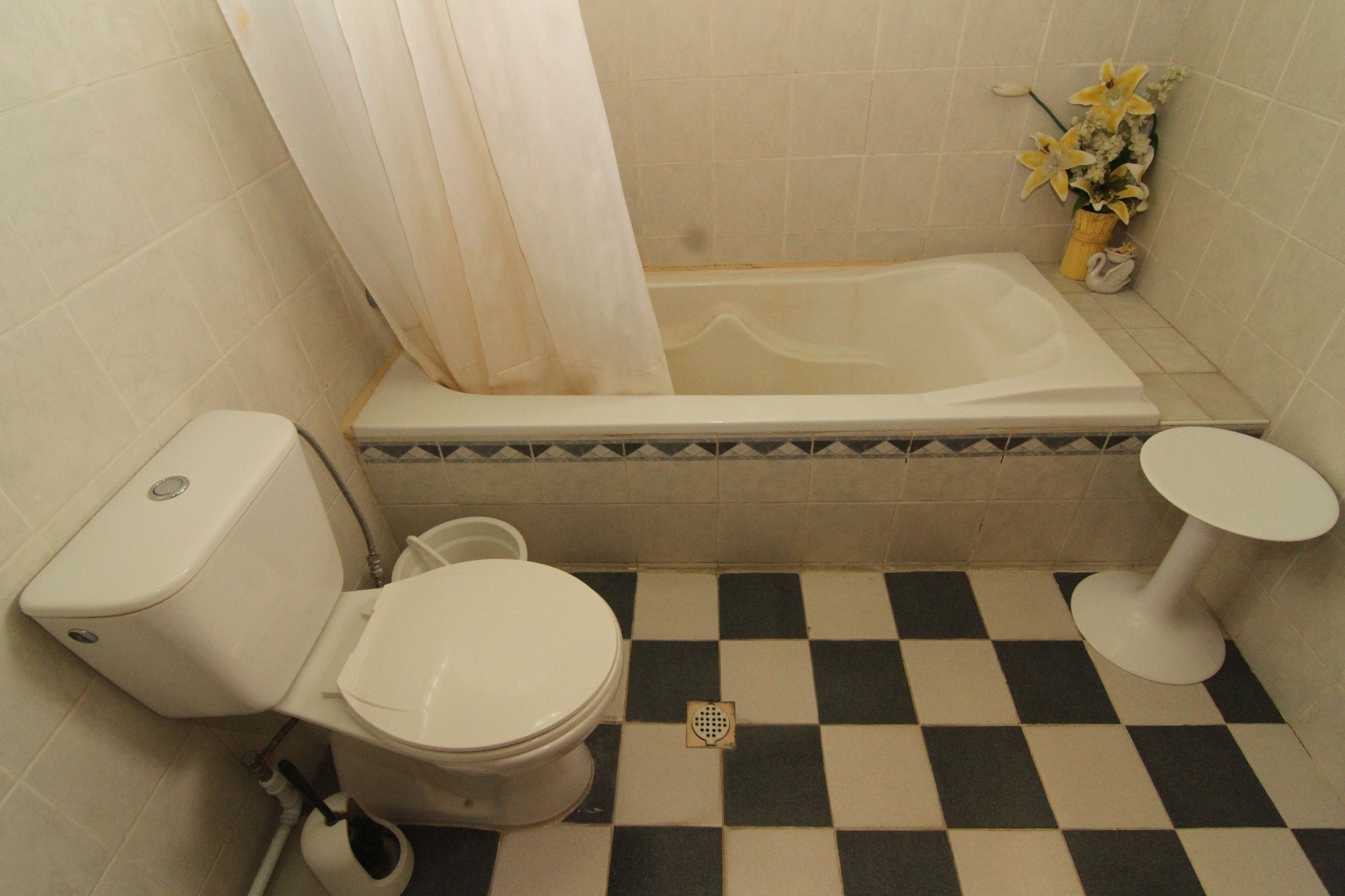 A bathroom with a toilet, bathtub, and a checkered floor.