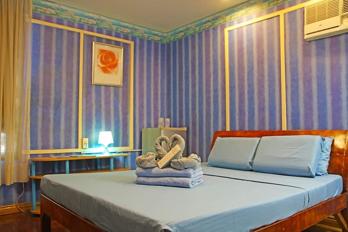 Una habitación de hotel con una cama, un escritorio, una lámpara y un cuadro en la pared.