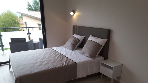 Un dormitorio moderno con una cama grande, una mesita de noche y vistas al exterior.