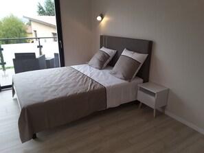 Un dormitorio moderno con una cama grande, una mesita de noche y vistas al exterior.
