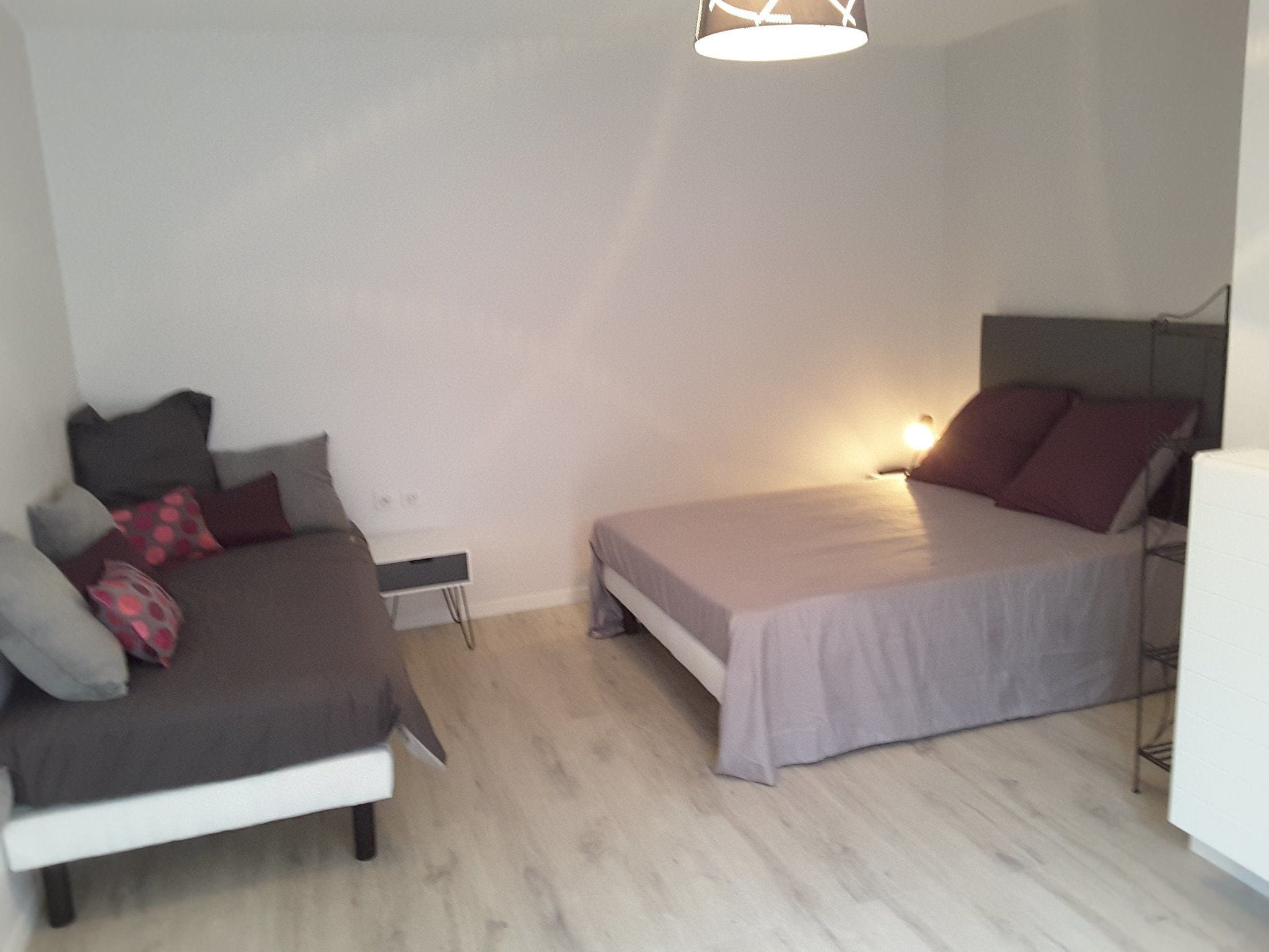Un dormitorio con dos camas, una mesita de noche y una lámpara colgante.