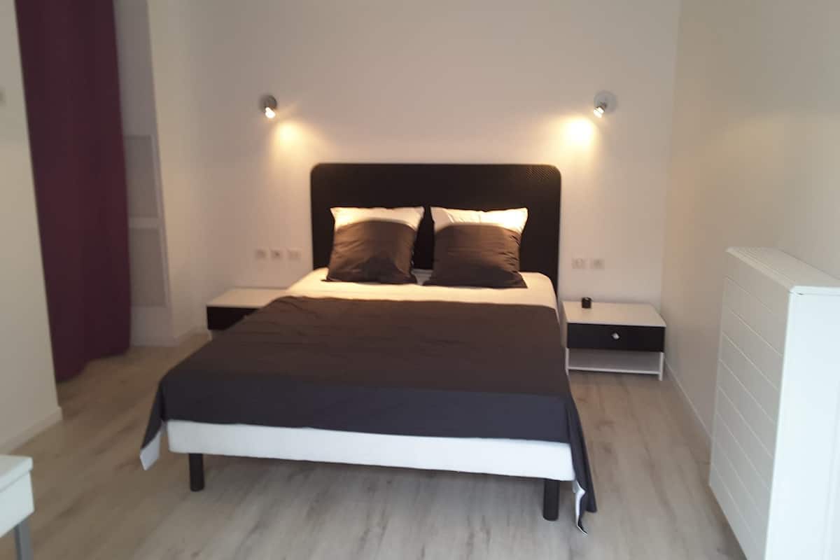 A modern bedroom with a bed, bedside tables, and a ceiling light fixture.