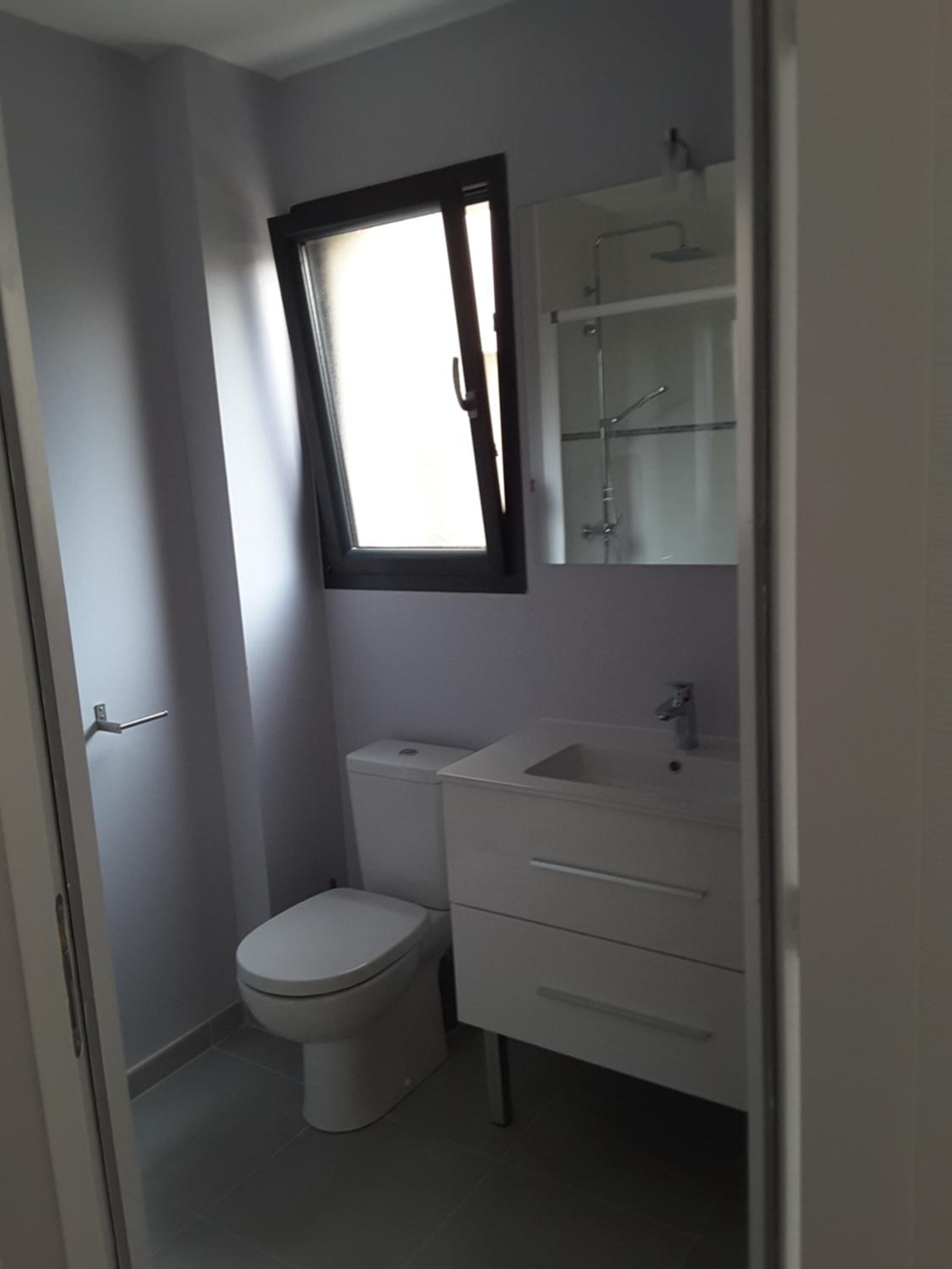 A small, modern bathroom with a toilet, sink, and mirror.