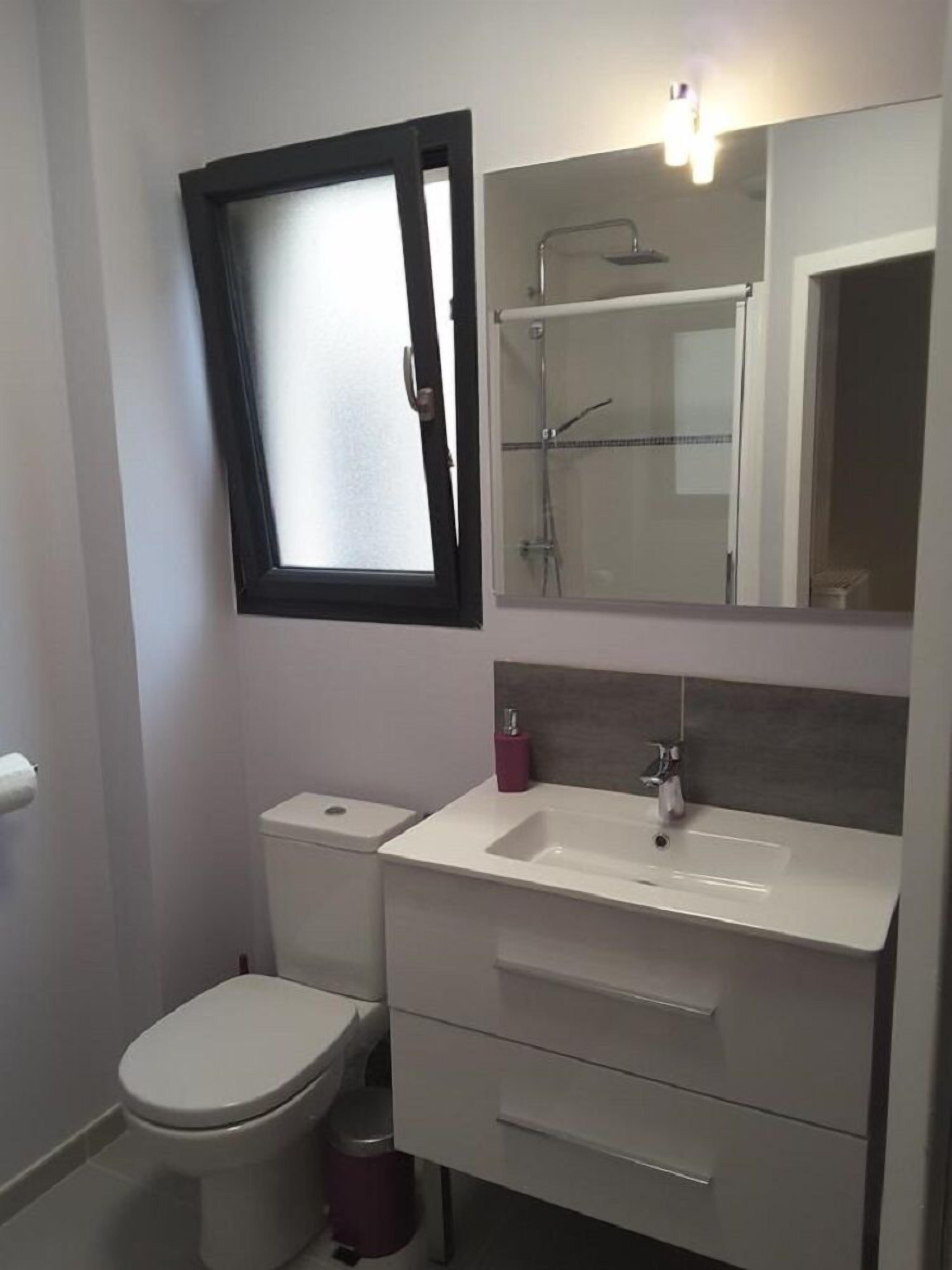 Un baño pequeño con inodoro, lavamanos y ducha.