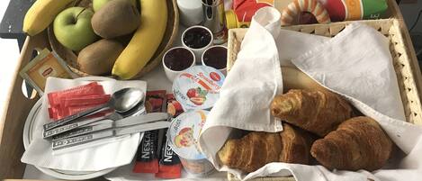 Una mesa de madera con diversos alimentos, entre ellos frutas, pan y salsas.