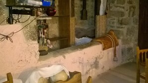 Une cuisine rustique avec un mur en pierre, des étagères en bois et un banc en bois.