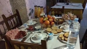 Une table à manger dressée avec divers aliments pour le petit-déjeuner, notamment des fruits, du pain et des condiments.