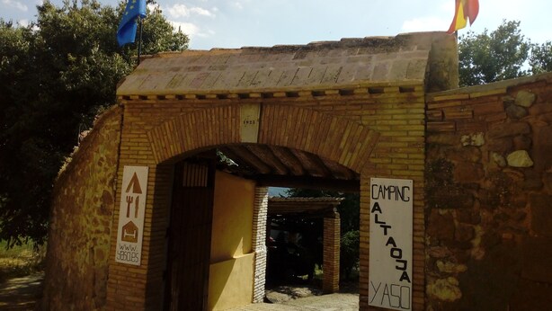 Une entrée en forme d’arche, construite en briques, avec une pancarte indiquant un espace de camping.
