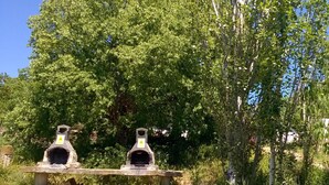 Deux constructions en pierre qui ressemblent à des fours, posées sur un banc de pierre dans une zone herbeuse, avec des arbres en arrière-plan.