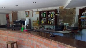 Un espace bar avec un comptoir en briques, des tabourets et des étagères remplies de bouteilles.