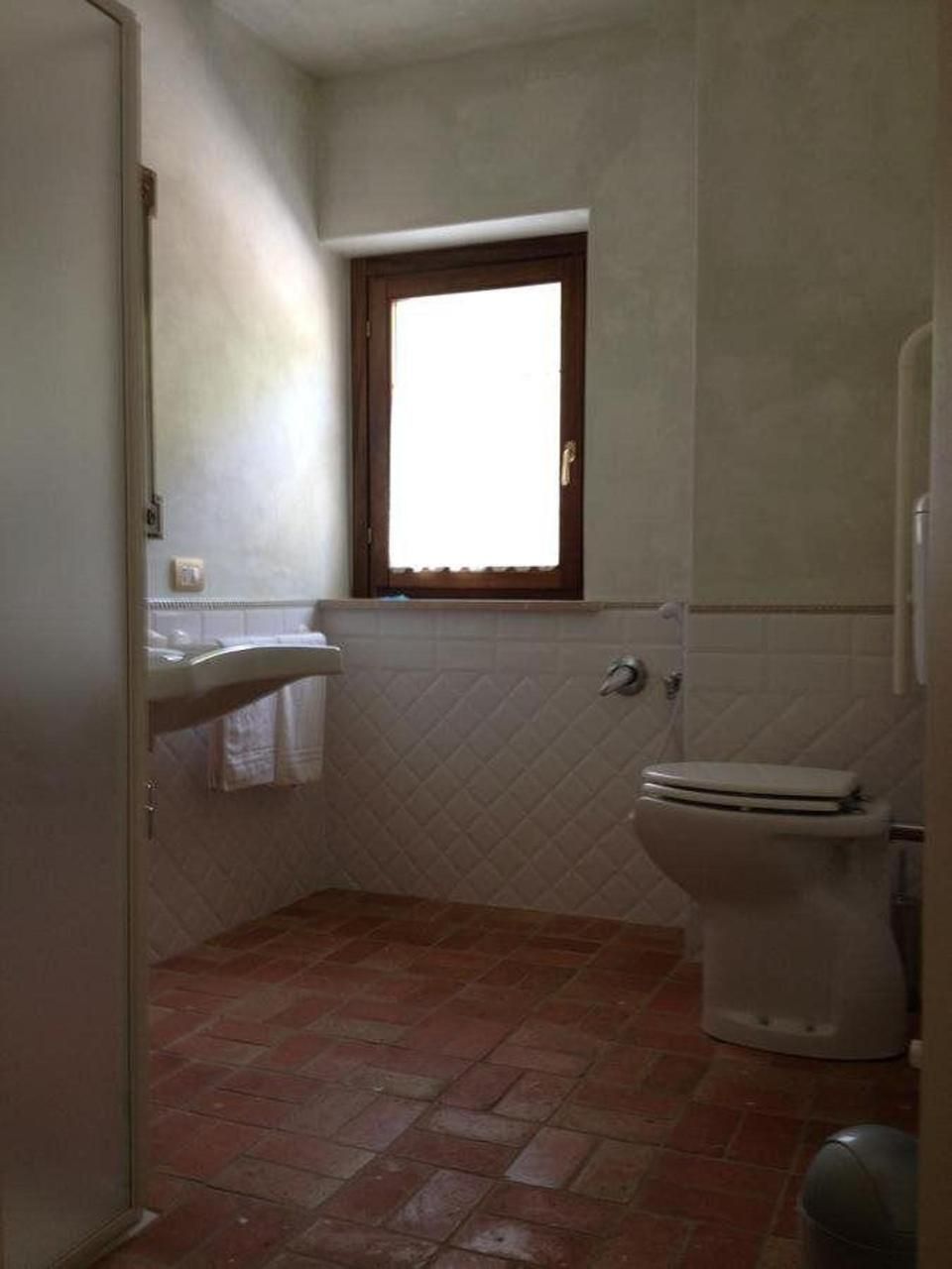A bathroom with a toilet, a window, and a sink.