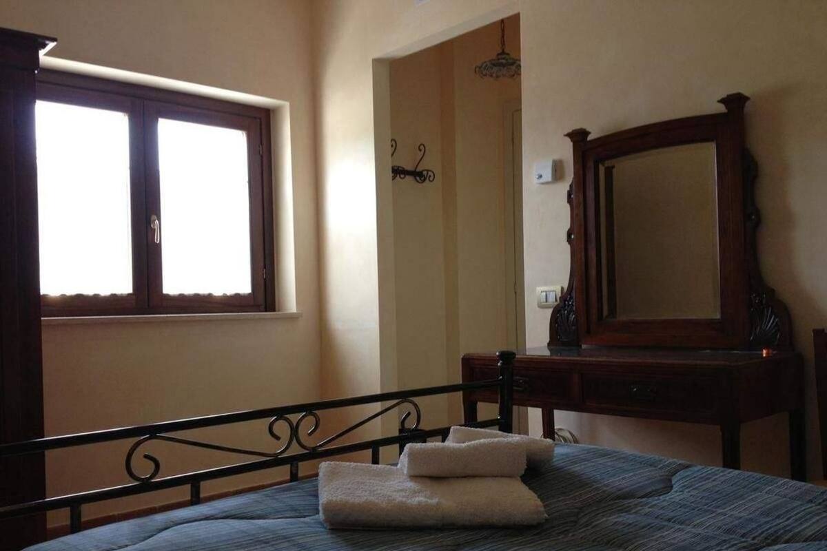 Un dormitorio con una cama, un aparador de madera, un espejo grande y una ventana.