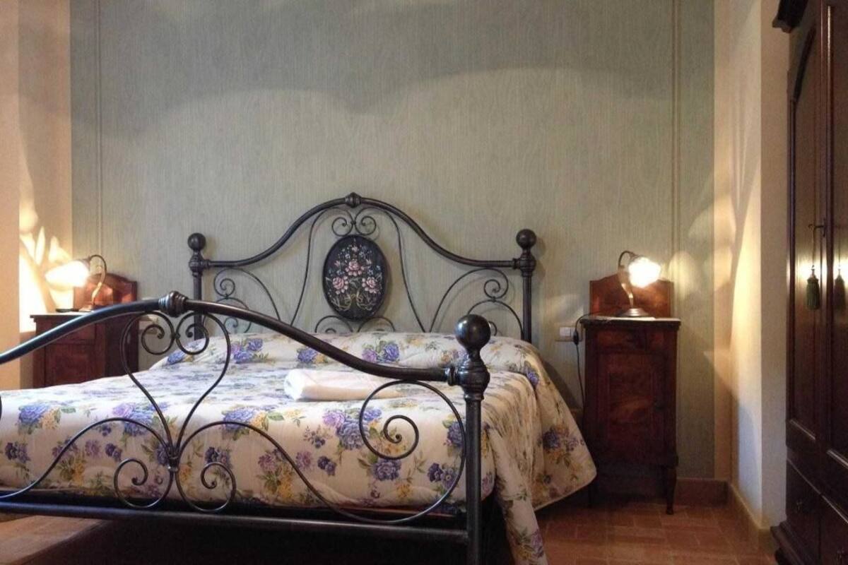 Una cama con cubrecama floral, un cabecero con diseño floral y dos mesitas de noche con lámparas.
