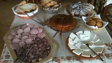 Una mesa de buffet con diversos alimentos, incluyendo pan, pasteles y un pastel.