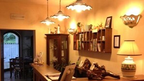 Un espace d’accueil avec un comptoir en bois, une lampe et une bibliothèque contenant divers objets.