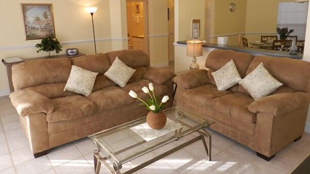 A living room with two brown sofas, a glass coffee table, and a ceiling fan.
