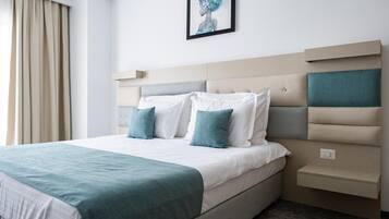 Una habitación de hotel moderna con una cama grande, cabecero con compartimentos de almacenamiento y una obra de arte enmarcada en la pared.