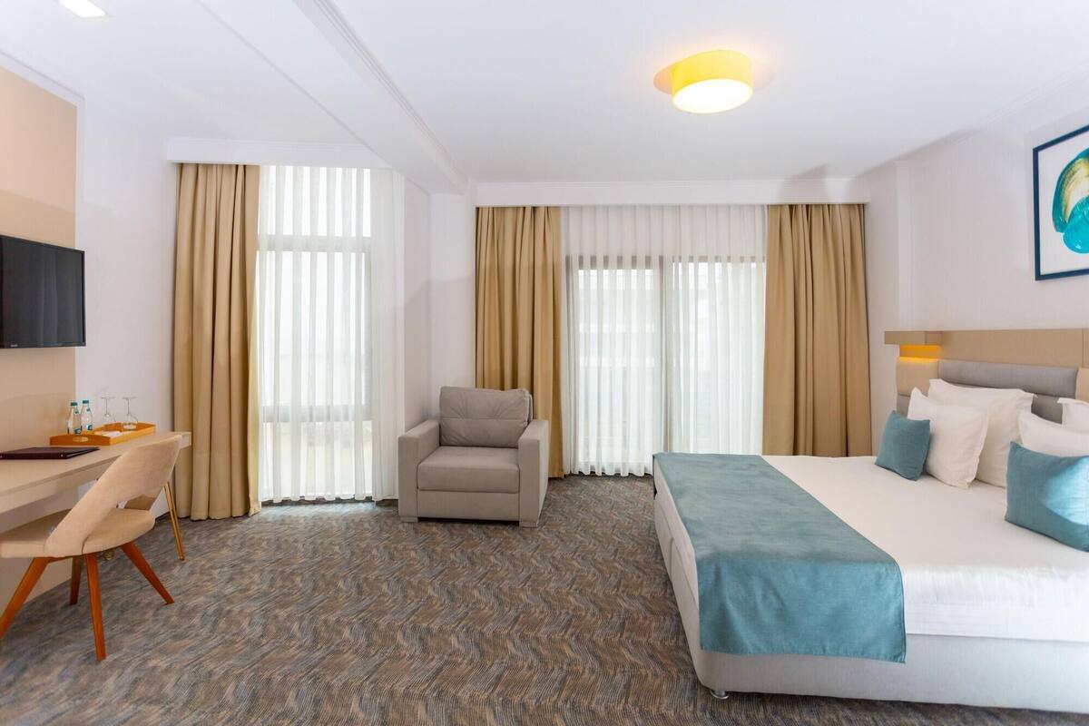 Una habitació d'hotel amb un llit, una taula de treball, una cadira i una televisió.