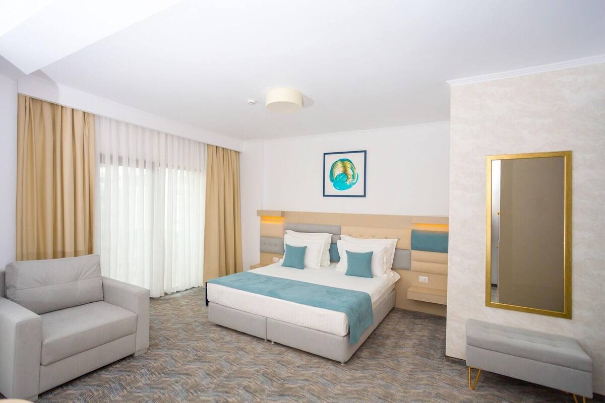 Una habitació d'hotel amb un llit, un sofà, un mirall i un quadre a la paret.