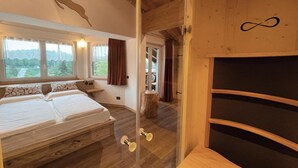 A bedroom with a bed, a window, a wooden ceiling, and a door with a wooden frame. - Hotel Al Lago (Folgaria)