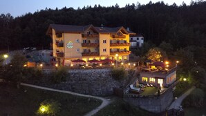 A multi-story hotel with outdoor seating and a pool area. - Hotel Al Lago (Folgaria)