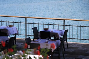 An outdoor dining area with tables and chairs, overlooking a body of water. - Hotel Al Lago (Folgaria)